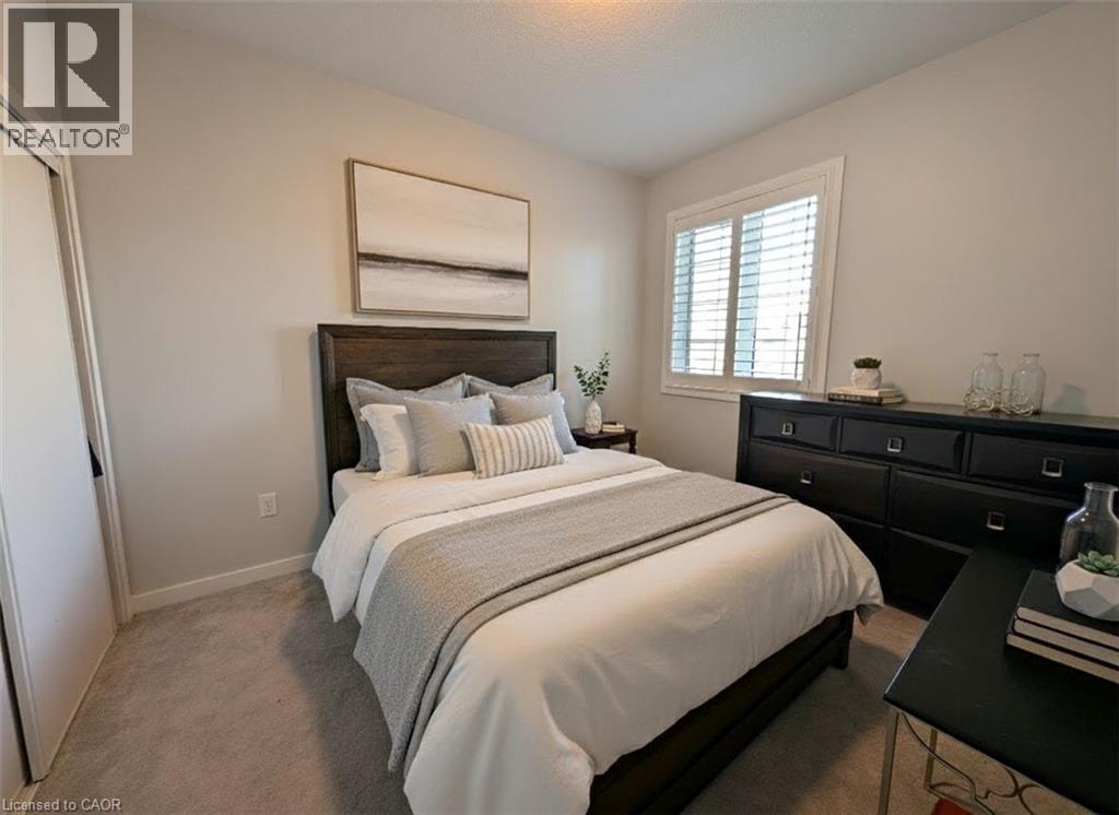 Bedroom featuring light gray wall paint, light gray carpet, and a white plantation-shutter window - 37 Mull Avenue, Caledonia, ON - Indoor Photo Showing Bedroom