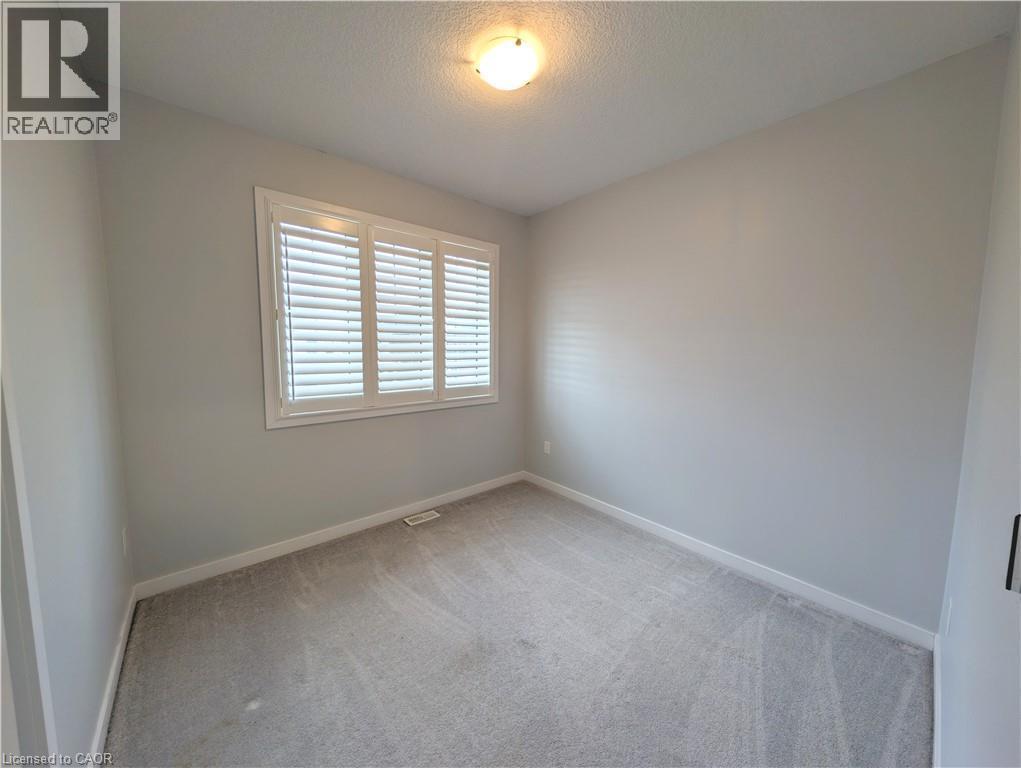 Neutral-toned room featuring a window with white plantation shutters, light gray walls, and gray carpeting - 37 Mull Avenue, Caledonia, ON - Indoor Photo Showing Other Room