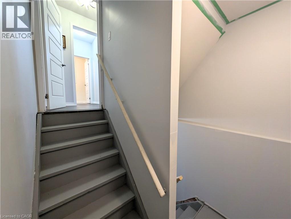 Staircase with a wood handrail, painted treads, and light gray walls - 37 Mull Avenue, Caledonia, ON - Indoor Photo Showing Other Room