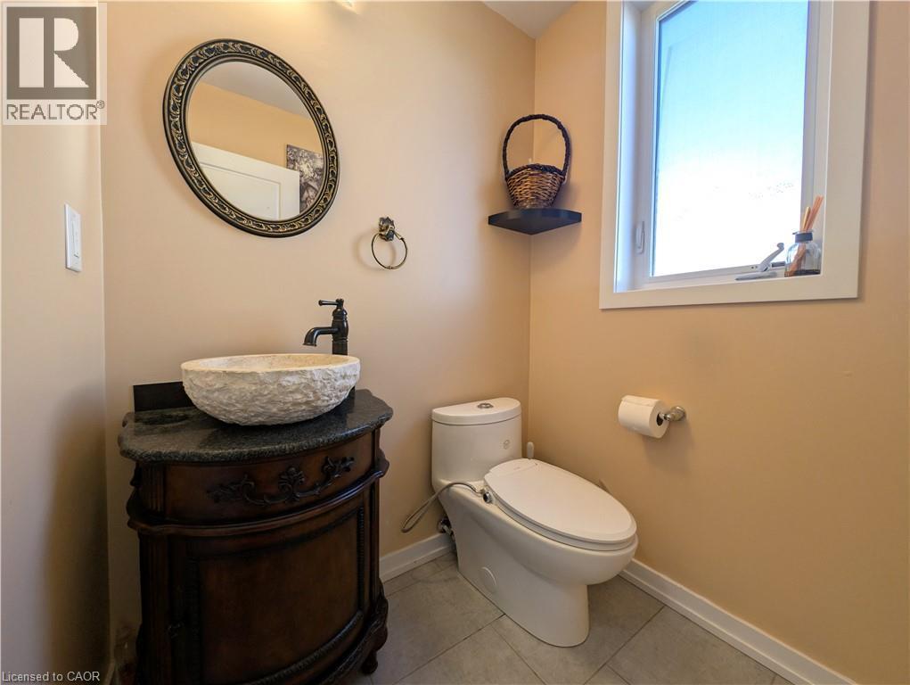 Wood-finish vanity with a vessel sink and dark stone countertop - 37 Mull Avenue, Caledonia, ON - Indoor Photo Showing Bathroom