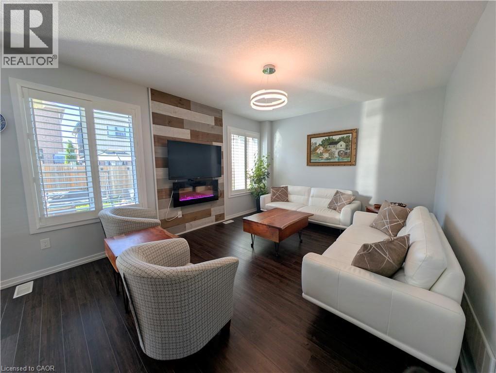 Spacious room featuring dark wood-finish flooring, light-colored walls, and a feature wall with horizontal wood paneling - 37 Mull Avenue, Caledonia, ON - Indoor Photo Showing Living Room