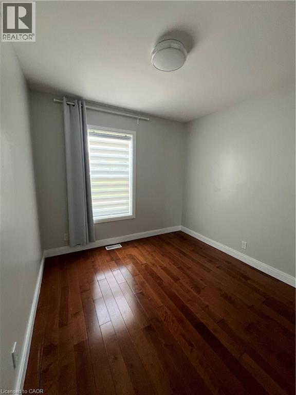 Refinished hardwood flooring, neutral wall paint, and a modern ceiling light fixture - 179 S Vine Street S, St. Catharines, ON