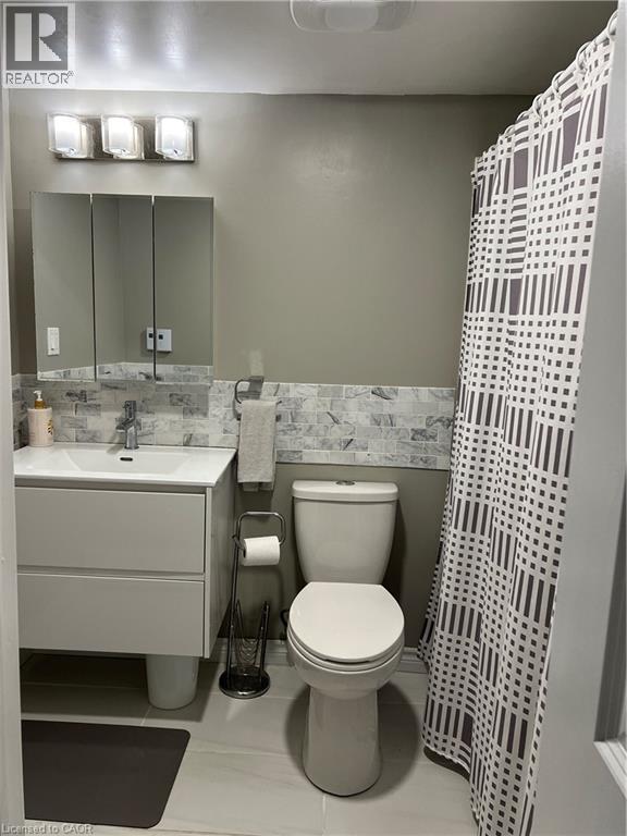 Modern bathroom featuring a contemporary vanity with integrated sink, a three-door medicine cabinet, and a multi-bulb vanity light fixture - 179 S Vine Street S, St. Catharines, ON
