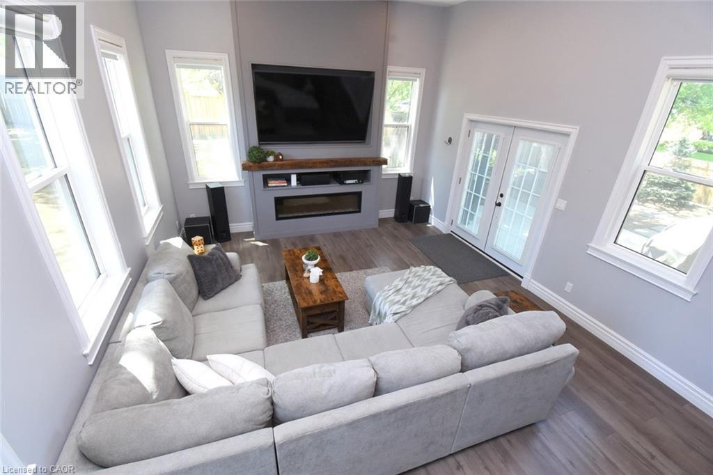 Spacious living area featuring a 12ft vaulted ceiling, contemporary fireplace with a wood mantle, and multiple windows providing natural light - 89 Lynden Road, Lynden, ON - Indoor Photo Showing Living Room