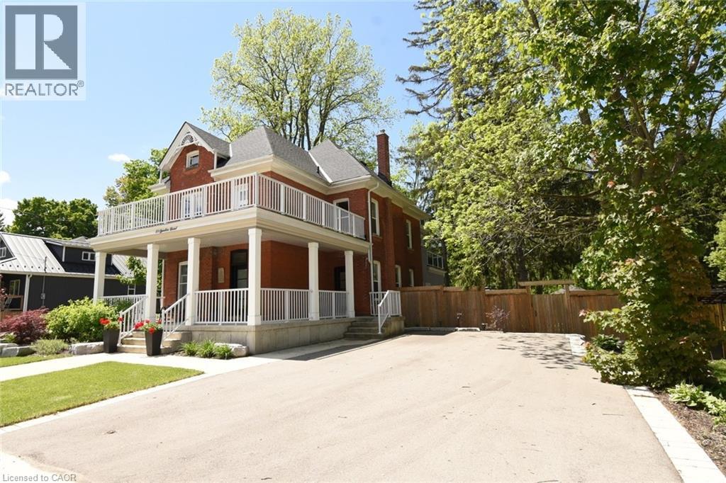 Red brick exterior featuring a full-width covered porch with white columns and railings. Also showing private double wide driveway - 89 Lynden Road, Lynden, ON