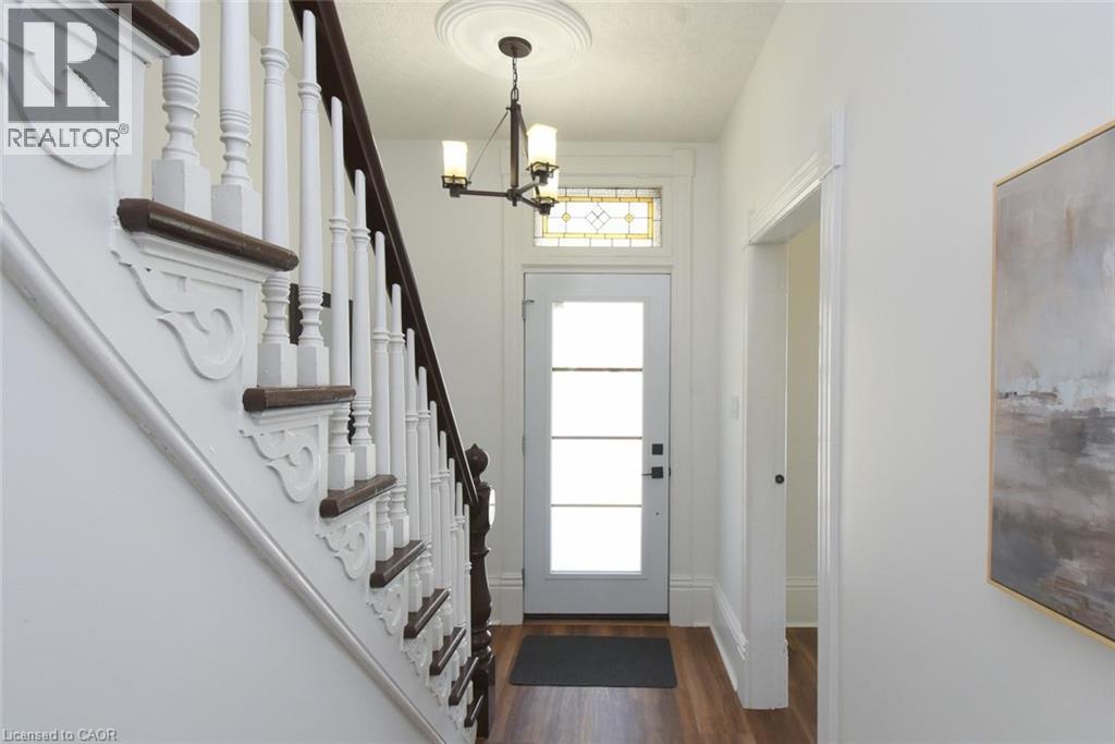 Foyer - detailed staircase with dark wood handrails and white balusters, and a front entry door featuring frosted glass panels and a stained glass transom - 89 Lynden Road, Lynden, ON