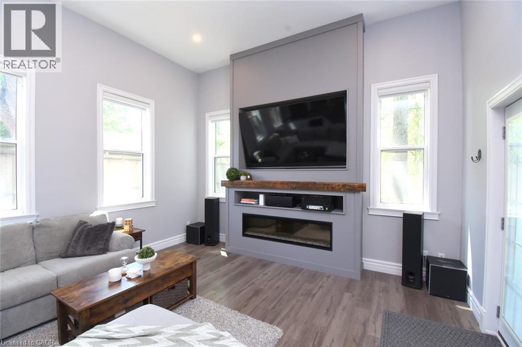 Family room featuring a built-in media console with an integrated linear electric fireplace and a rustic wood mantle - 89 Lynden Road, Lynden, ON