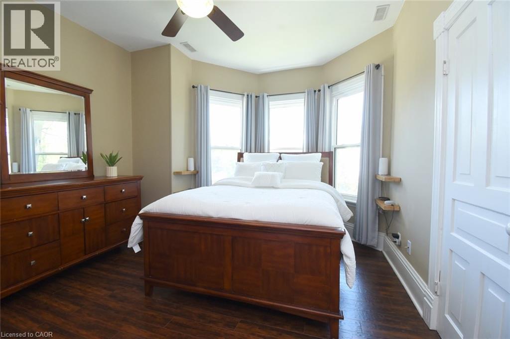 Spacious room featuring wood-finish flooring, a ceiling fan, and a three-panel bay window - 89 Lynden Road, Lynden, ON