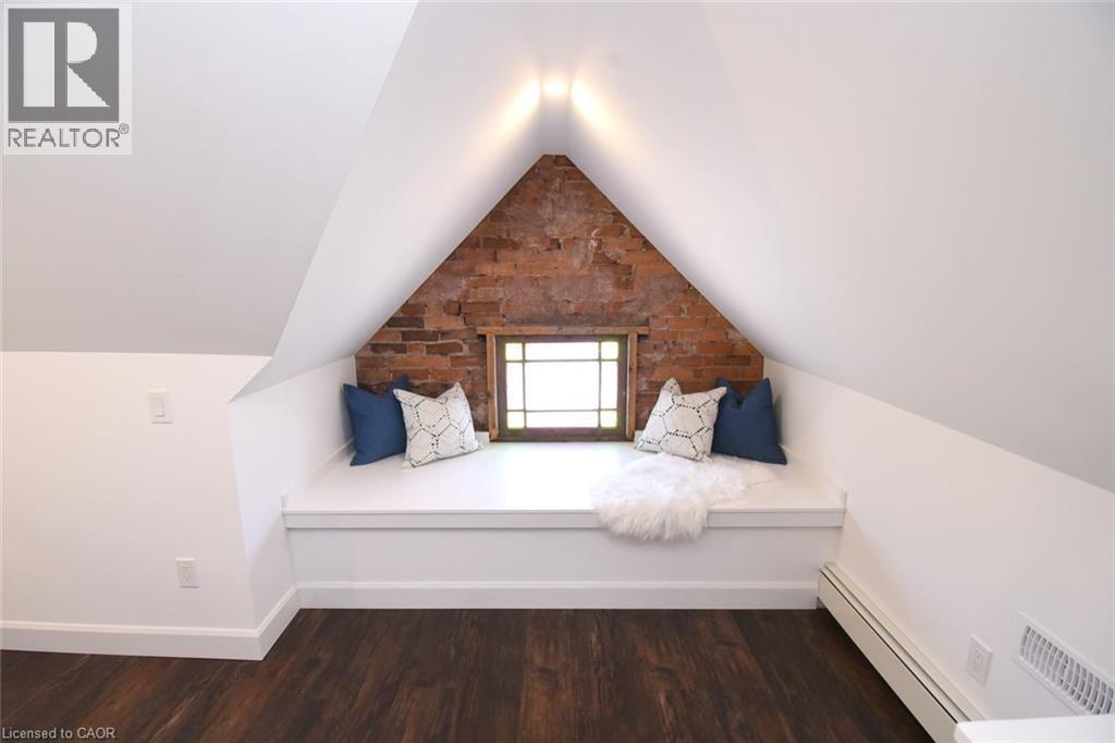 Built-in window seat with exposed brick accent wall, stained glass wood-frame window, and recessed lighting - 89 Lynden Road, Lynden, ON