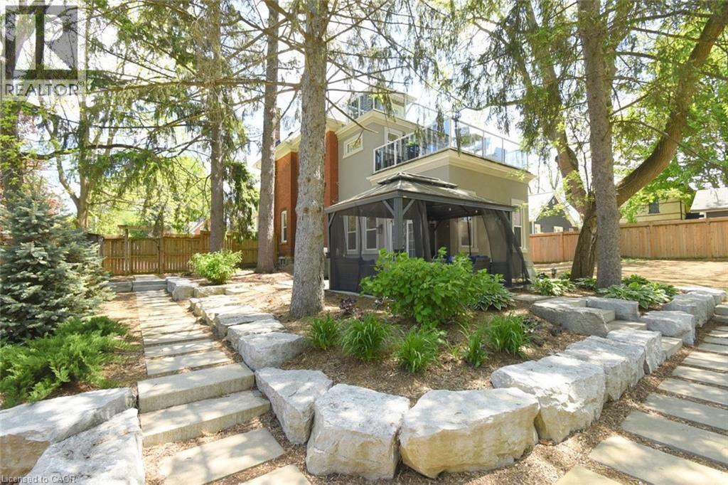Backyard featuring a stone paver pathway, large boulder retaining wall, and mature trees - 89 Lynden Road, Lynden, ON
