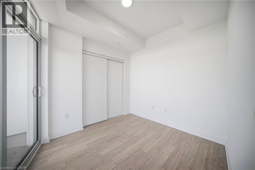 Room featuring light wood-finish flooring, white walls, and a sliding glass door providing exterior access - 2782 Barton Street E Unit# 516, Hamilton, ON - Indoor Photo Showing Other Room