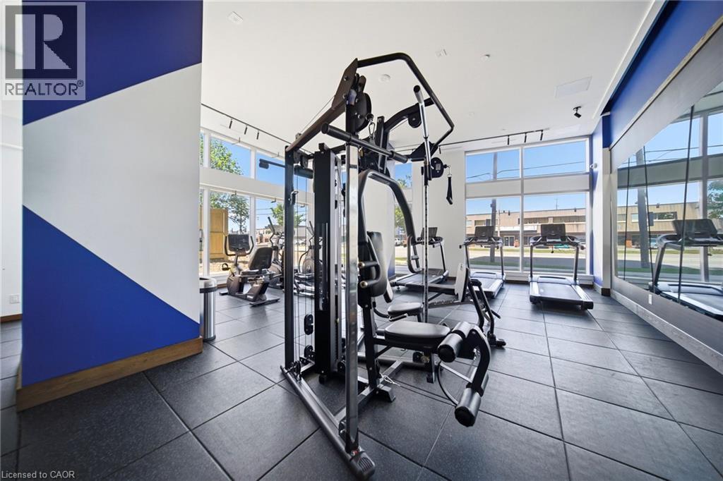 Dedicated fitness center featuring rubberized flooring, abundant natural light from expansive windows, track lighting, and a mirrored wall - 2782 Barton Street E Unit# 516, Hamilton, ON - Indoor Photo Showing Gym Room