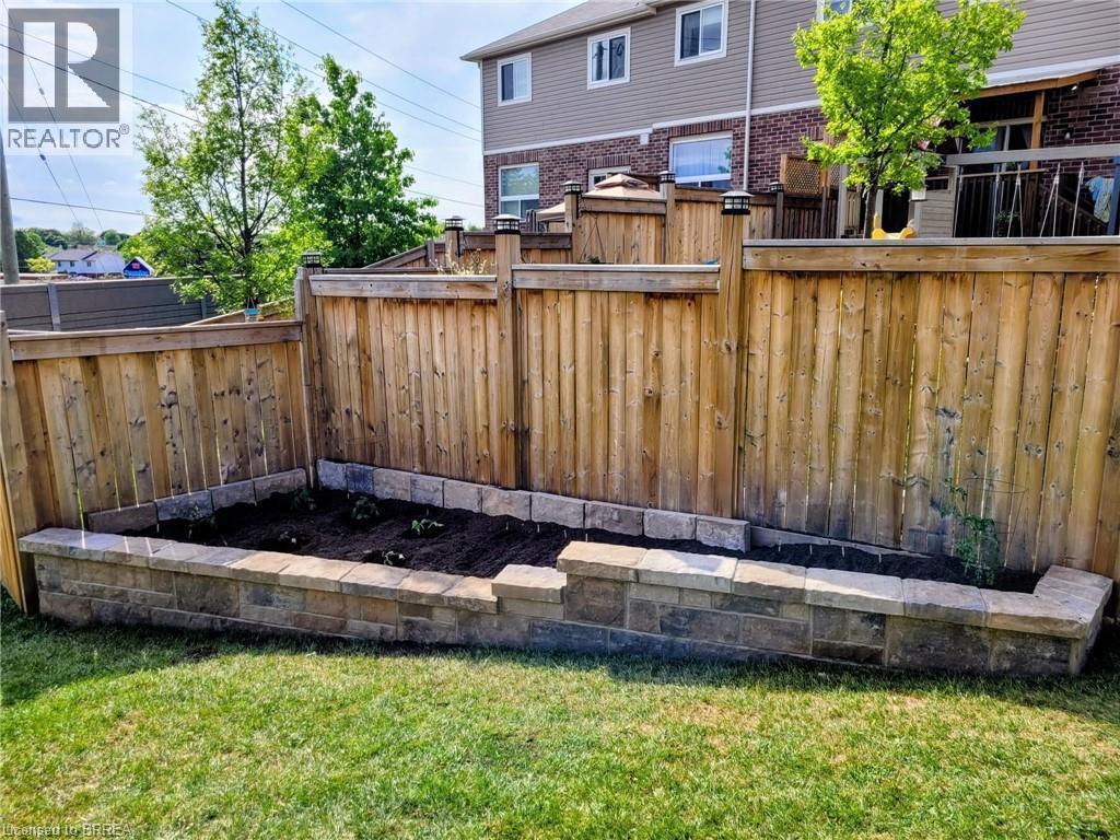Manicured lawn with a stone-bordered raised garden bed - 100 Chester Drive Unit# 16, Cambridge, ON - Outdoor With Exterior