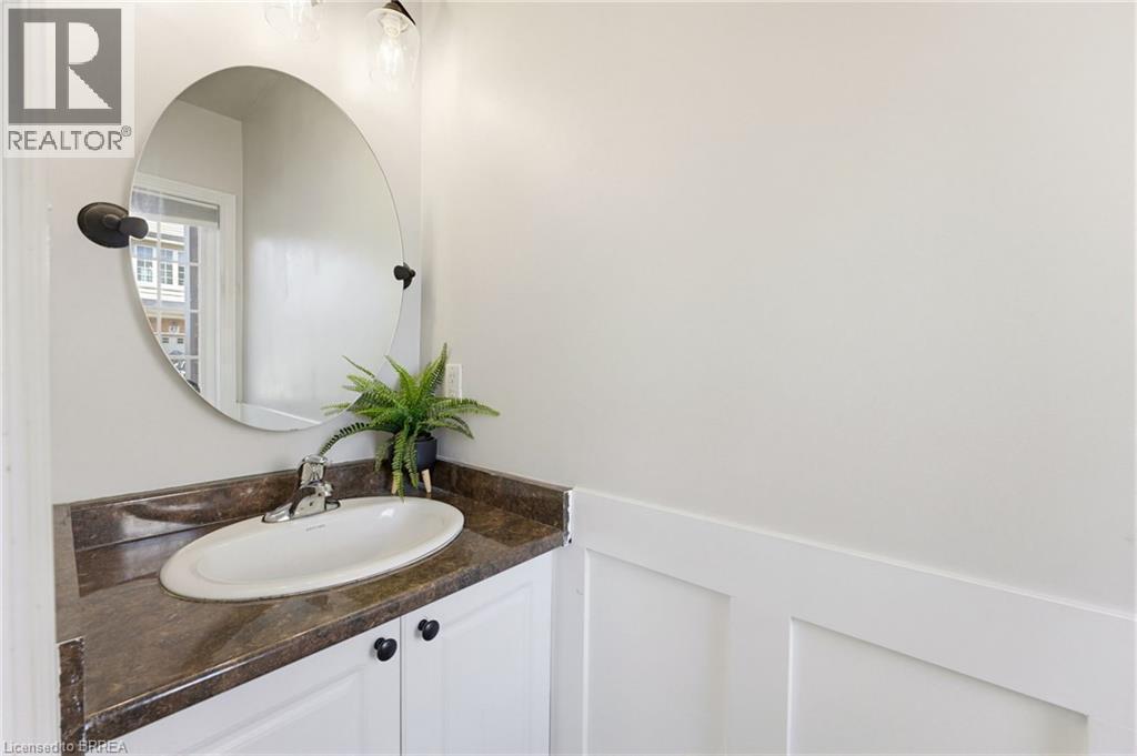 Bathroom vanity featuring a white oval undermount sink, dark countertop, and white cabinetry with black hardware - 100 Chester Drive Unit# 16, Cambridge, ON - Indoor Photo Showing Bathroom