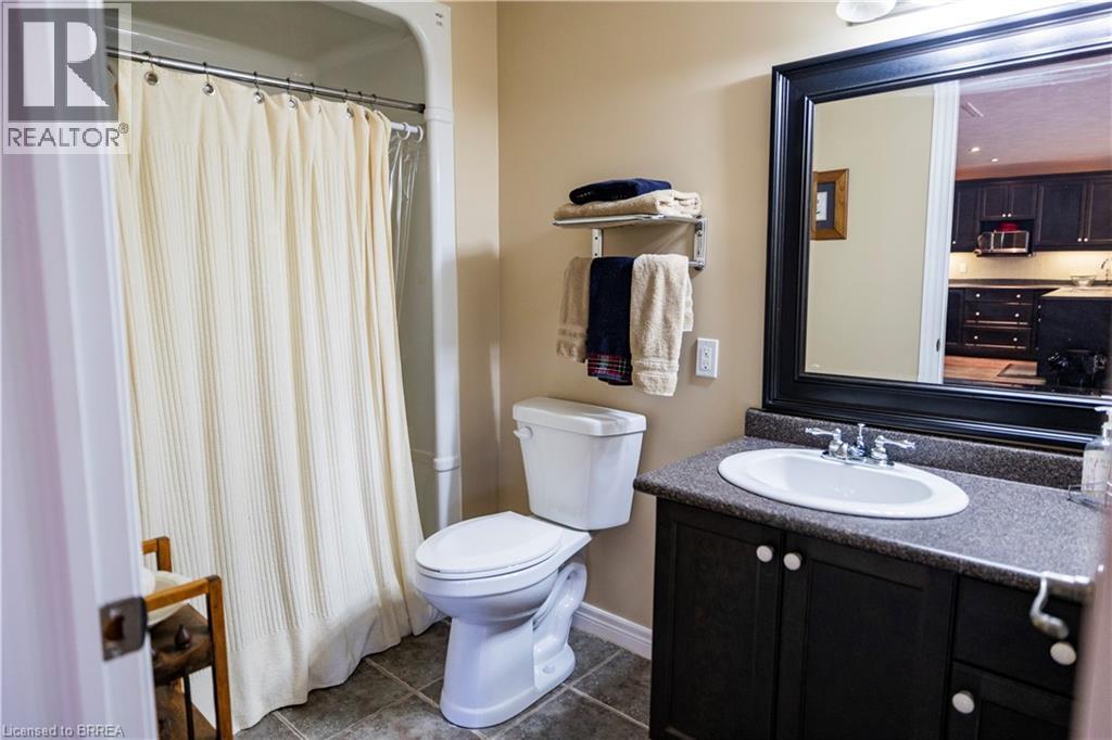 Bathroom featuring a shower/tub combination, floor-set toilet, and a vanity with a dark countertop and under-sink storage - 100 Mechanic Street W, Waterford, ON - Indoor Photo Showing Bathroom
