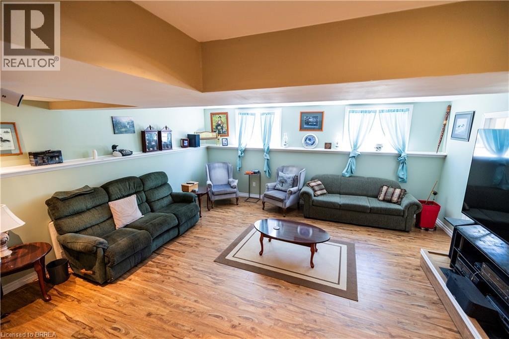 Spacious recreational room featuring wood-finish flooring and a partial wall with display ledge - 100 Mechanic Street W, Waterford, ON - Indoor Photo Showing Living Room