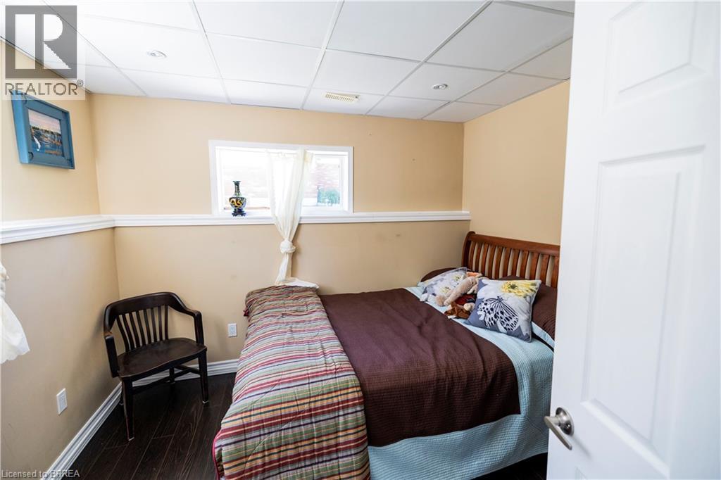 Compact room with dark wood-finish flooring, light tan walls, and white trim - 100 Mechanic Street W, Waterford, ON - Indoor Photo Showing Bedroom