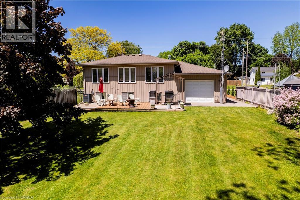 Expansive backyard with a large grass area, wood privacy fencing, and mature perimeter trees - 100 Mechanic Street W, Waterford, ON - Outdoor