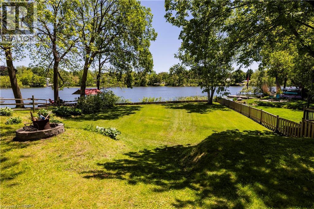 Expansive waterfront lawn with mature trees and a stone-lined fire pit - 100 Mechanic Street W, Waterford, ON - Outdoor With View