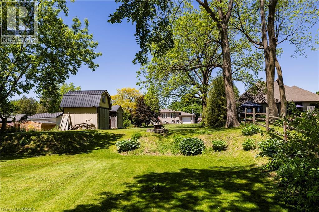 Expansive green lawn with mature trees providing dappled shade - 100 Mechanic Street W, Waterford, ON - Outdoor