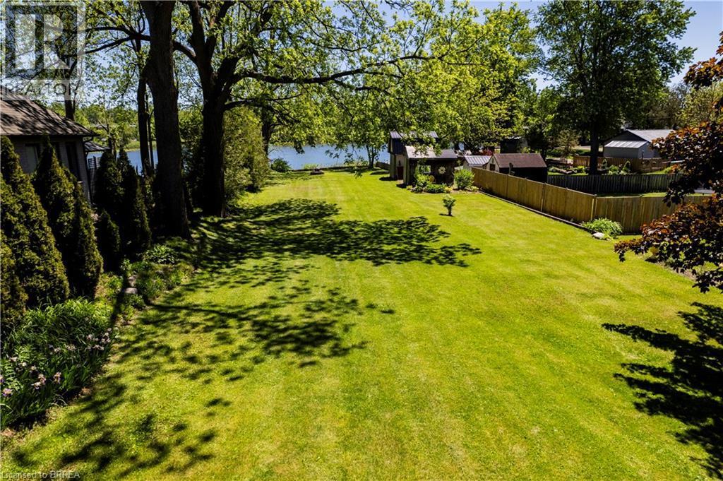 Expansive green lawn with mature trees and a partial water feature visible in the background - 100 Mechanic Street W, Waterford, ON - Outdoor