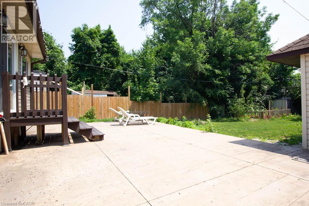 Expansive concrete patio area with a wooden privacy fence - 30 Eastvale Place, Hamilton, ON - Outdoor