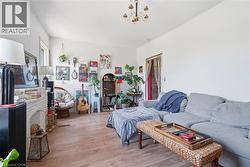 Spacious living area featuring wood-finish flooring, a white brick fireplace surround, and a classic chandelier -