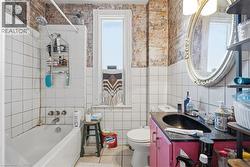 Bathroom featuring white square wall tiling, a white bathtub, and a window with white trim -