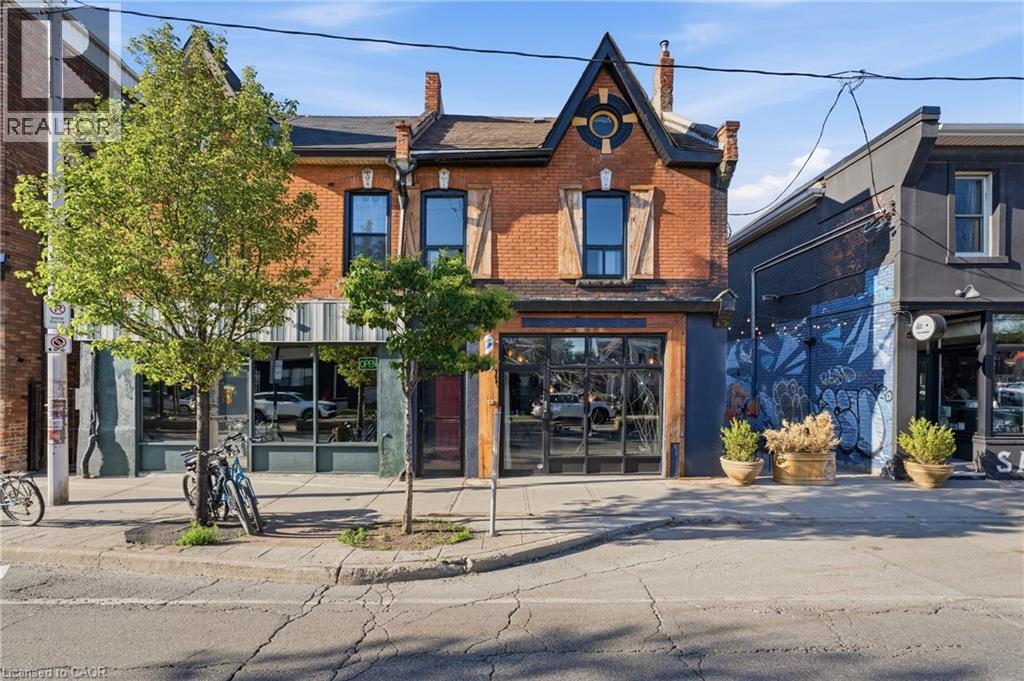 Brick facade building with a prominent peaked gable, featuring a lower level with large pane windows and an upper level with two windows framed by decorative wooden shutters - 355 Barton Street E, Hamilton, ON - Outdoor