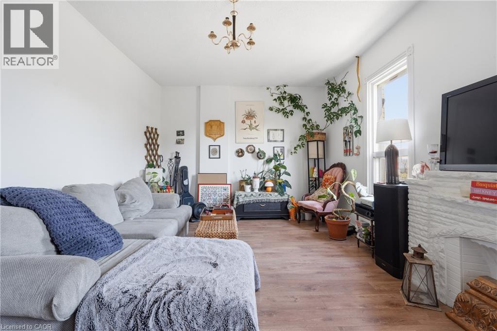 Bright living space featuring wood-finish flooring, a white-painted brick fireplace, and a window with natural light - 355 Barton Street E, Hamilton, ON - Indoor Photo Showing Living Room