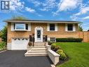 Brick facade residence featuring an attached garage, bay window, landscaped front yard with block retaining walls, and a paved driveway - 107 Rosslinn Road, Cambridge, ON  - Outdoor 