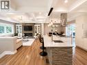 Open-concept living space featuring wood-finish flooring, a stacked stone kitchen island with a double basin sink, and a coffered ceiling - 107 Rosslinn Road, Cambridge, ON  - Indoor With Fireplace 