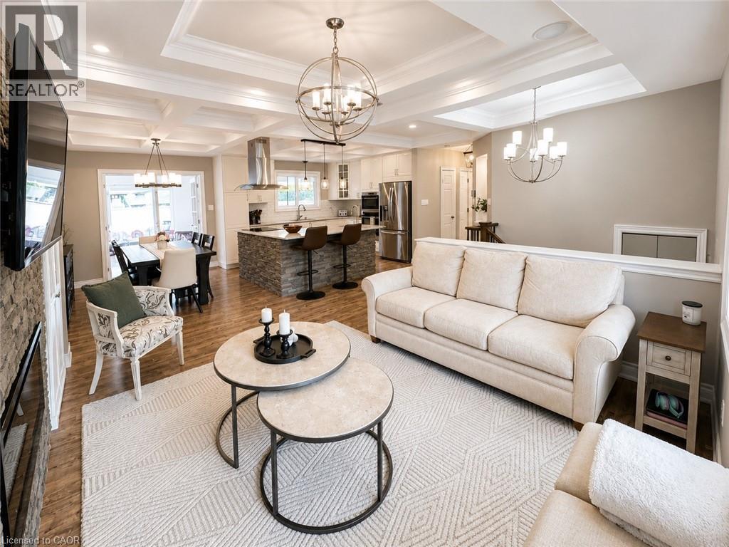 Open-concept living space featuring coffered ceilings, wood-finish flooring, and a stacked stone fireplace surround - 107 Rosslinn Road, Cambridge, ON - Indoor Photo Showing Living Room With Fireplace