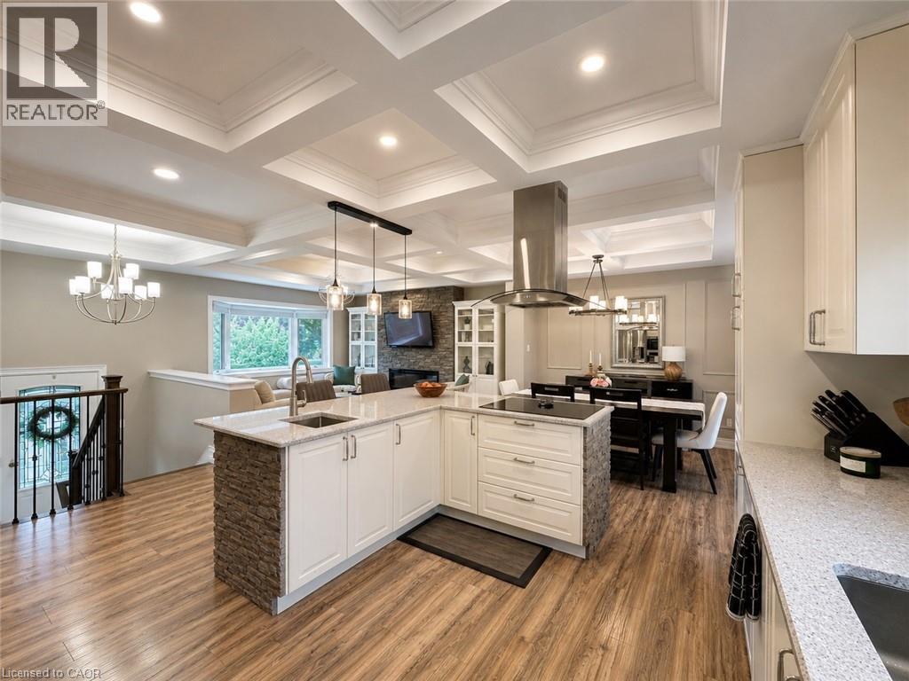 Open-concept kitchen featuring an island with stacked stone accents, a built-in cooktop, and a stainless steel range hood - 107 Rosslinn Road, Cambridge, ON - Indoor Photo Showing Other Room
