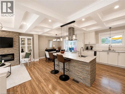 Open-concept living space with coffered ceilings, wood-finish flooring, and a stone-clad fireplace - 107 Rosslinn Road, Cambridge, ON - Indoor With Fireplace