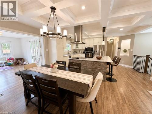 Open-concept living space with coffered ceilings, wood-finish flooring, and a kitchen featuring a stone-clad island with a light-colored countertop - 107 Rosslinn Road, Cambridge, ON - Indoor Photo Showing Dining Room