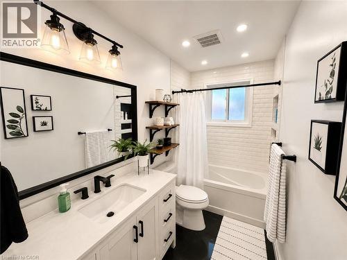 Bathroom featuring a white vanity with integrated sink, matte black fixtures, and a large framed mirror - 107 Rosslinn Road, Cambridge, ON - Indoor Photo Showing Bathroom