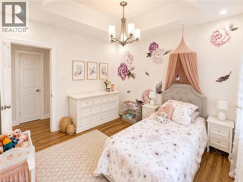 Room featuring wood-finish flooring, a tray ceiling with recessed lighting, and a multi-arm chandelier - 107 Rosslinn Road, Cambridge, ON - Indoor Photo Showing Bedroom