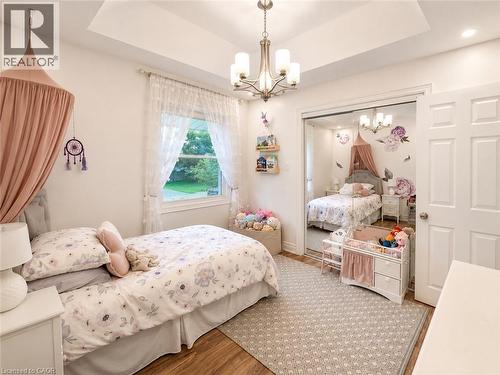 Interior room featuring wood-finish flooring, a tray ceiling, and a chandelier with glass shades - 107 Rosslinn Road, Cambridge, ON - Indoor Photo Showing Bedroom