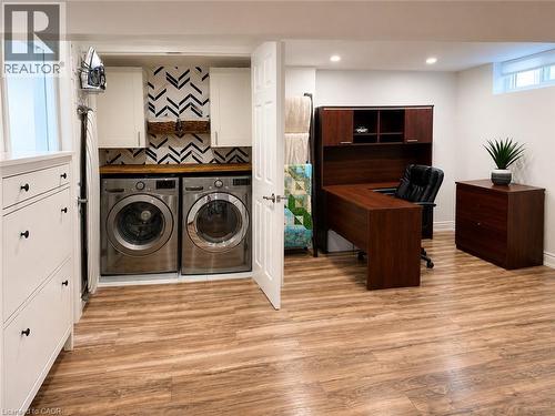 Dedicated laundry area featuring a wood-finish countertop, front-loading appliances, and chevron-patterned wall tile - 107 Rosslinn Road, Cambridge, ON - Indoor Photo Showing Laundry Room