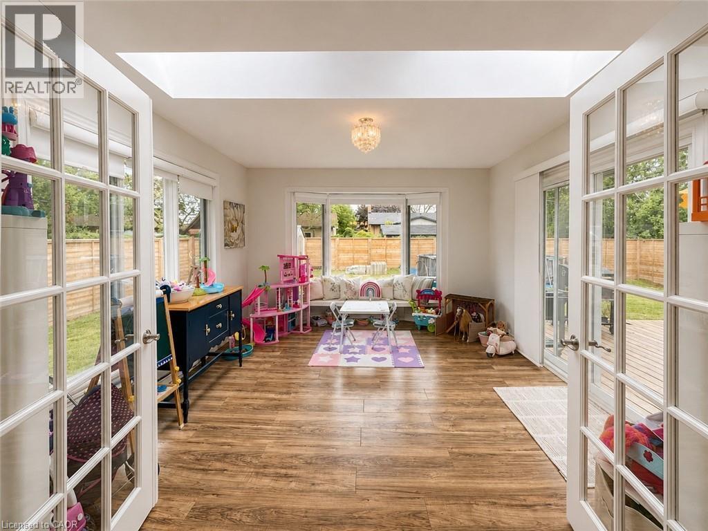 Bright, spacious room featuring wood-finish flooring and a central chandelier - 107 Rosslinn Road, Cambridge, ON - Indoor Photo Showing Other Room