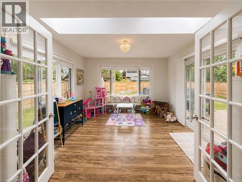 Bright, spacious room featuring wood-finish flooring and a central chandelier - 107 Rosslinn Road, Cambridge, ON - Indoor Photo Showing Other Room