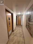 Hallway featuring neutral-toned tile flooring, recessed ceiling lighting, and a light wood-finish door with a louvered vent -