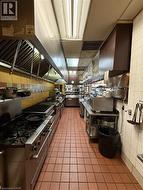 Commercial kitchen with extensive stainless steel countertops, multiple gas ranges, and a full-length exhaust hood system -