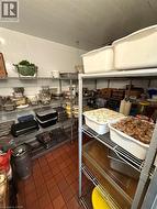 Commercial walk-in cooler featuring white panel walls, terracotta-toned tile flooring, and multi-tier wire shelving -