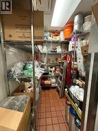 Commercial storage area featuring extensive metal wire shelving, tiled flooring, and overhead fluorescent lighting -