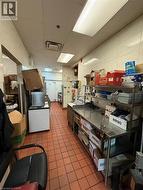 Commercial kitchen featuring terracotta-style tile flooring and stainless steel work surfaces -