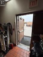 Commercial exit door with a metal grate threshold and terracotta-toned floor tiling -