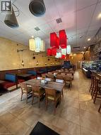 Spacious dining area featuring neutral-toned tile flooring, booth seating, and multiple pendant light fixtures -