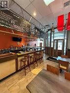 Full-service bar featuring bar seating, tile flooring, and overhead menu boards -
